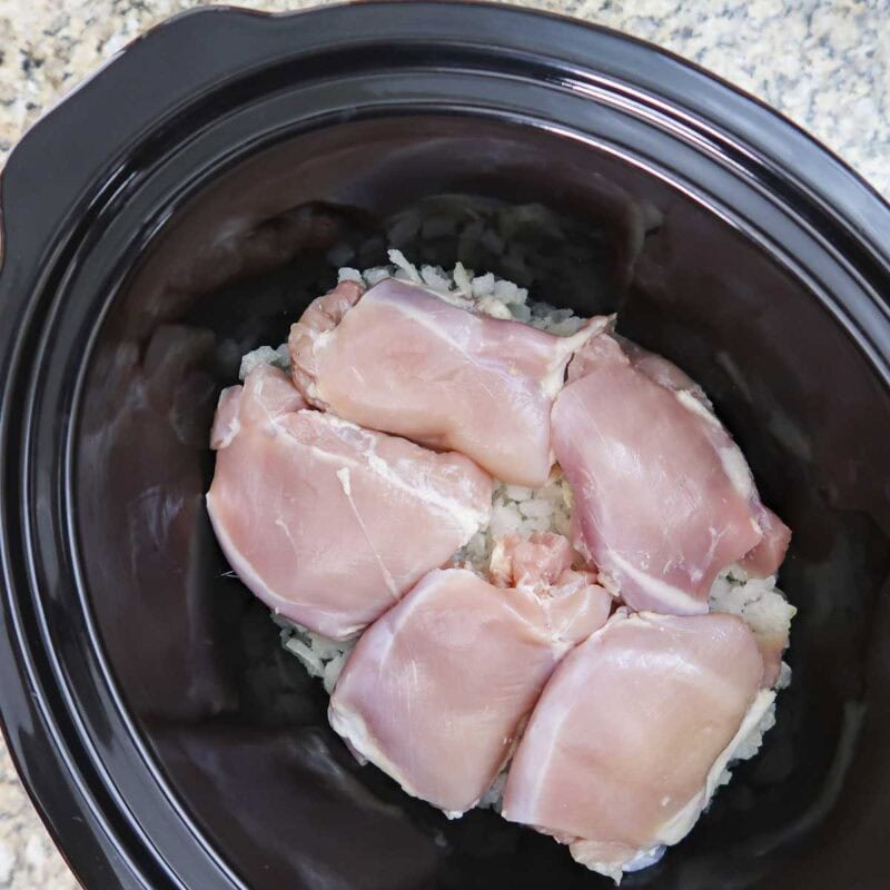 Overhead view of process shot 1 - place the onion in the crock pot and layer the chicken on top of the onion.