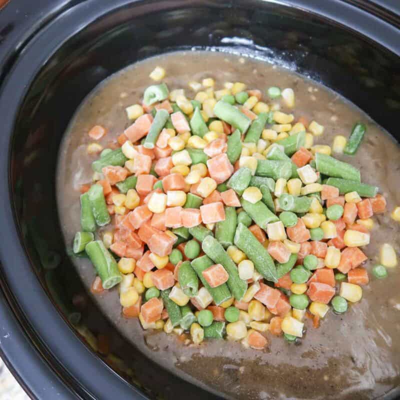 Overhead view of process shot 5 - add in the mixed veggies, re-cover, and cook until they are heated through, about another 20 minutes.
