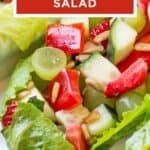 Side close up shot of two lettuce boats filled with fruit and veggie salad on a white plate.