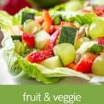 Side close up shot of a lettuce boat filled with fruit and veggie salad on a white plate.
