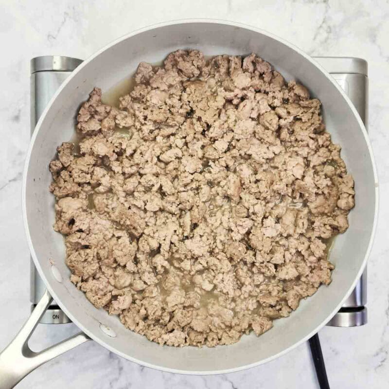 Overhead view of process shot 1 - heat a large skillet over medium-high heat. Add the ground turkey and break it up with a spatula, cooking about 5-6 minutes until it is no longer pink.