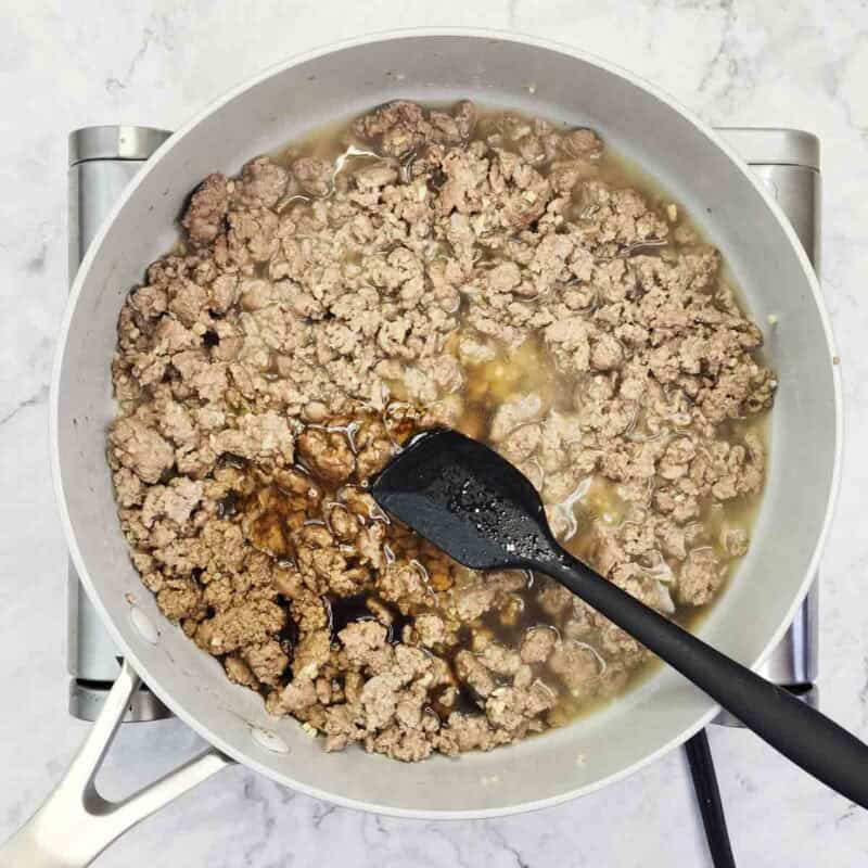 Overhead view of process shot 3 - pour the soy sauce and honey directly into the pan with the turkey, then mix and cook until the sauce starts to bubble.