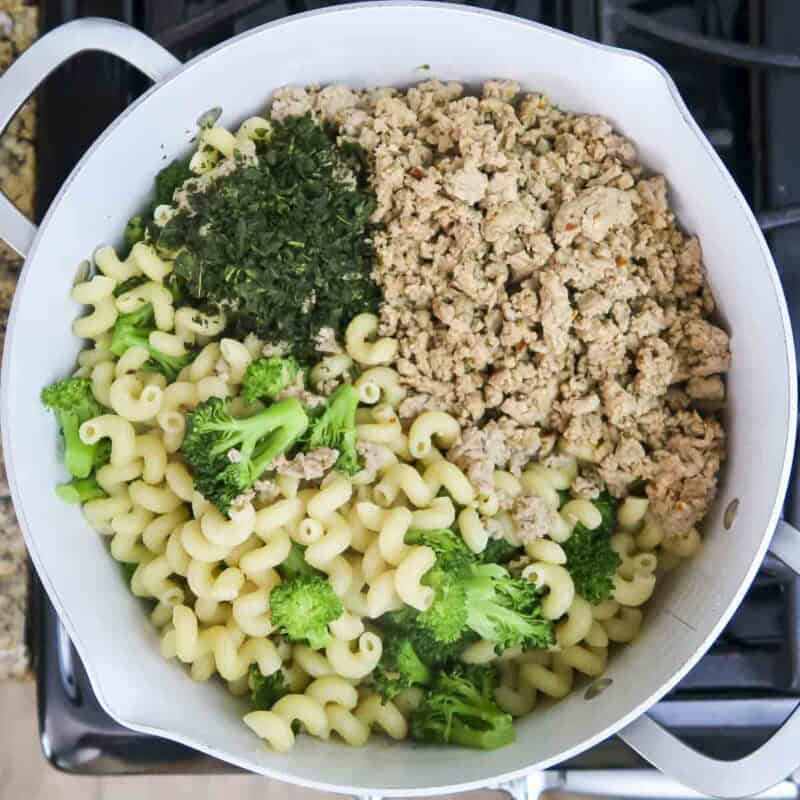 Overhead view of process shot 4 - add the turkey mixture, the remaining olive oil, and the fresh basil to the pasta pot. Mix until combined.