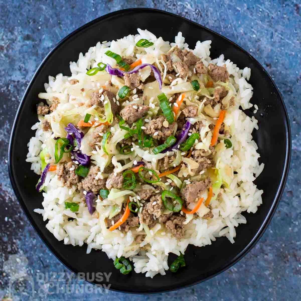Overhead shot of a ground turkey bowl garnished with fresh green onions in a black bowl.