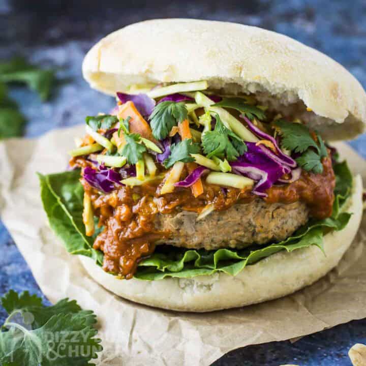 Side close up shot of thai turkey burger garnished with fresh parsley on a piece of brown parchment paper.