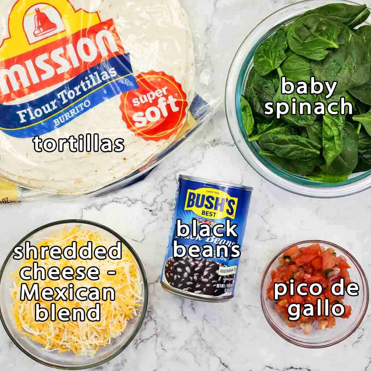 Overhead view of ingredients - tortillas, baby spinach, black beans, pico de gallo, and shredded cheese - mexican blend.