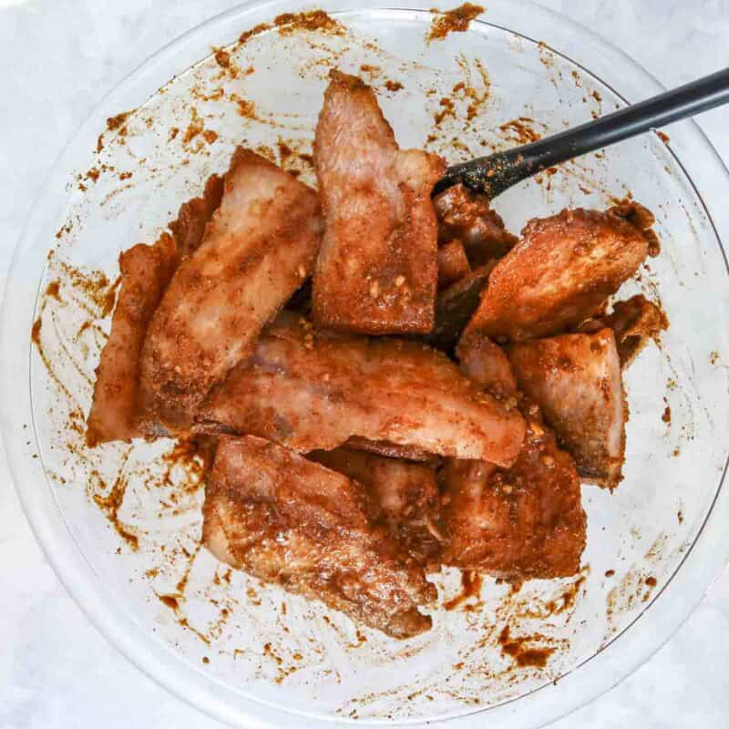 Overhead view of process shot 1 - combine the lime juice, cumin, paprika, garlic, salt, and pepper in a large bowl. Add in the tilapia and mix until coated.