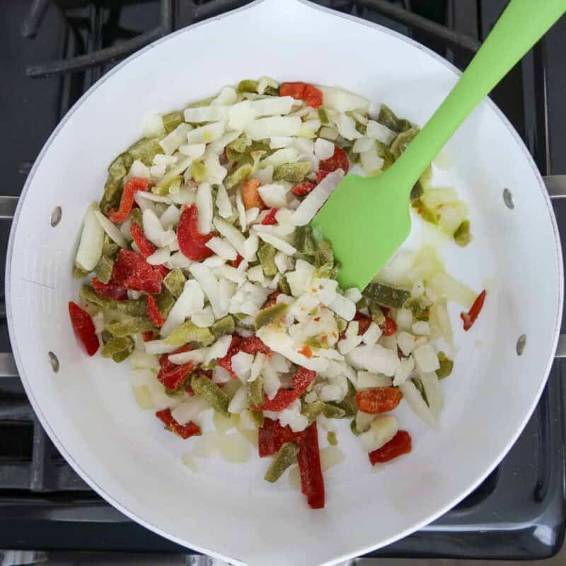 Overhead view of process shot 2 - heat the olive oil in a large skillet over medium-high heat. Add the peppers and onions until they begin to thaw, about 3 minutes.