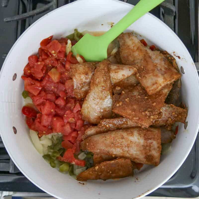 Overhead view of process shot 3 - add the tomatoes and marinated tilapia and mix them in.