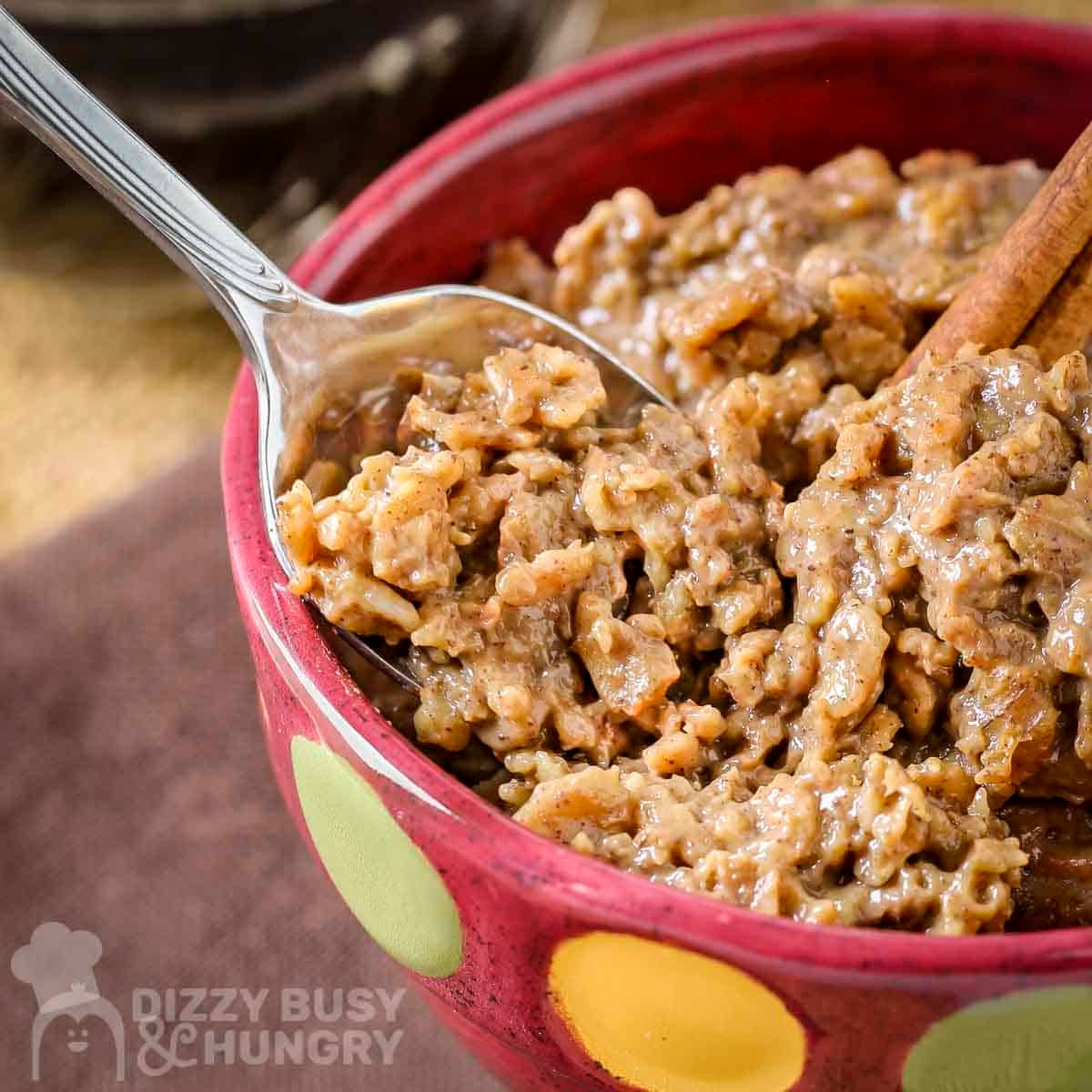Side close up shot of instant coffee oatmeal in a red bowl with green and yellow polka dots with a spoon taking a scoop.