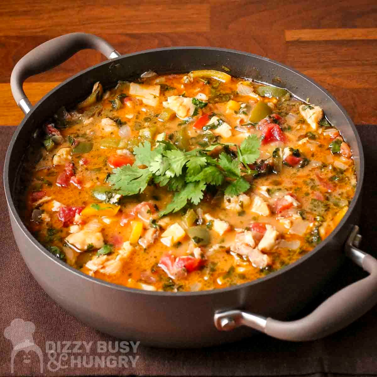 Side view of stew in brown pot on a brown placemat.