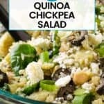 Side close up shot of quinoa salad in a glass bowl with a black spoon on a blue surface.