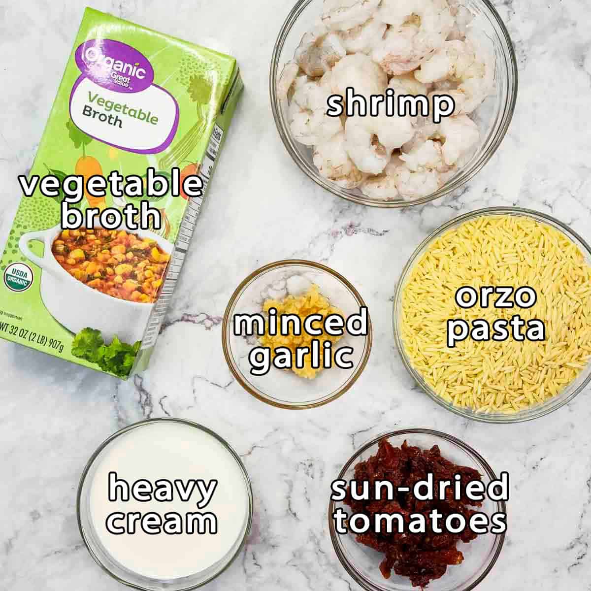 Overhead shot of ingredients - vegetable broth, shrimp, minced garlic, orzo pasta, heavy cream, and sun-dried tomatoes.