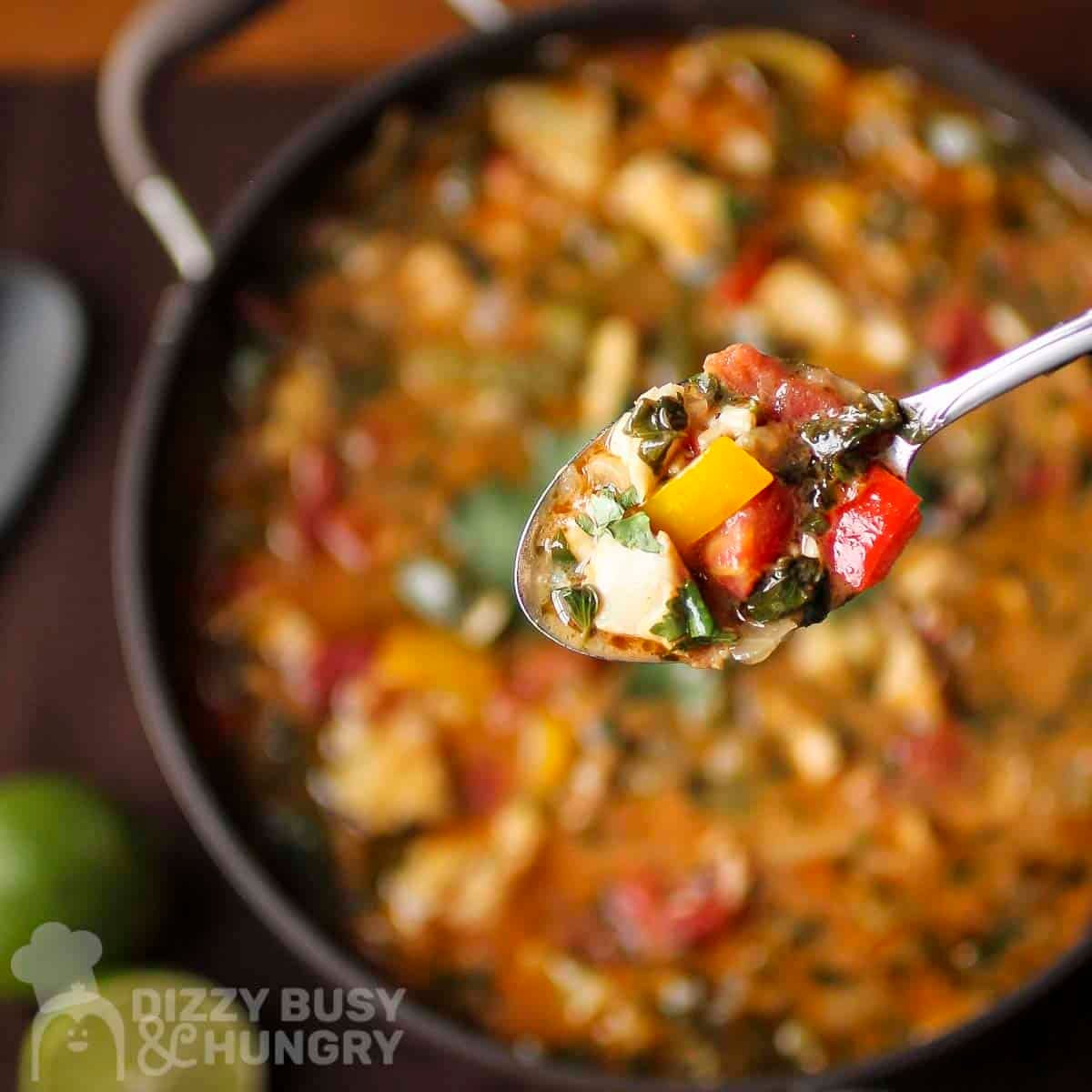 Overhead shot of a spoon holding a bite of stew over a pot full of stew.