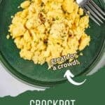 Overhead shot of scrambled eggs garnished with fresh herbs on a sage green plate with a fork on the side.