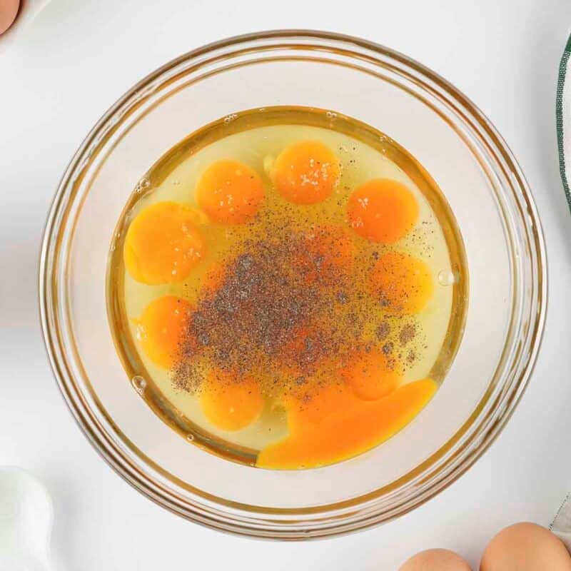 Overhead view of process shot 1 - add the eggs into a medium mixing bowl with the salt and pepper.