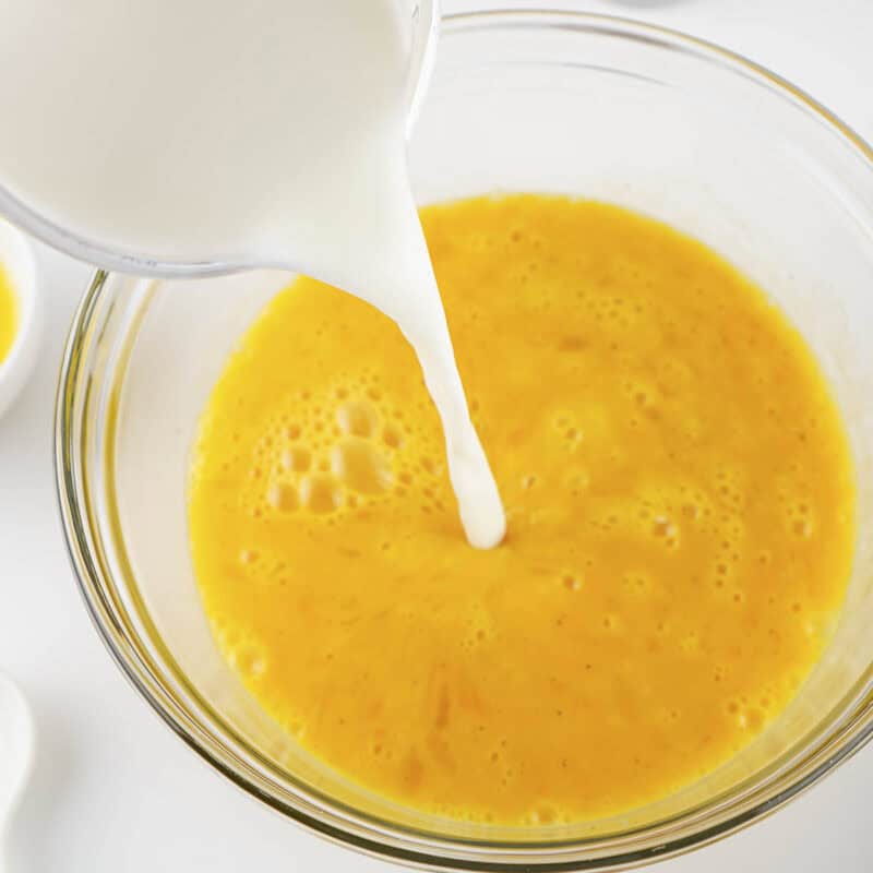 Overhead view of process shot 2 - beat until the yolks are broken and add the milk. Continue to beat until the mixture is uniformly smooth.