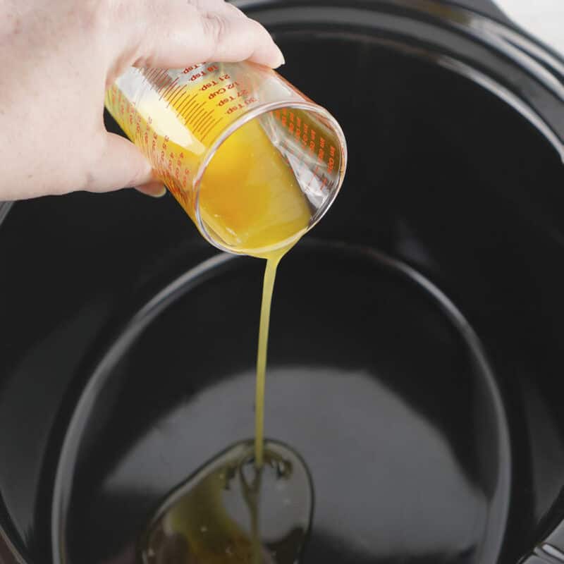 Overhead view of process shot 3 - pour the melted butter into the crockpot and spread it evenly around the bottom and a couple of inches up the sides.