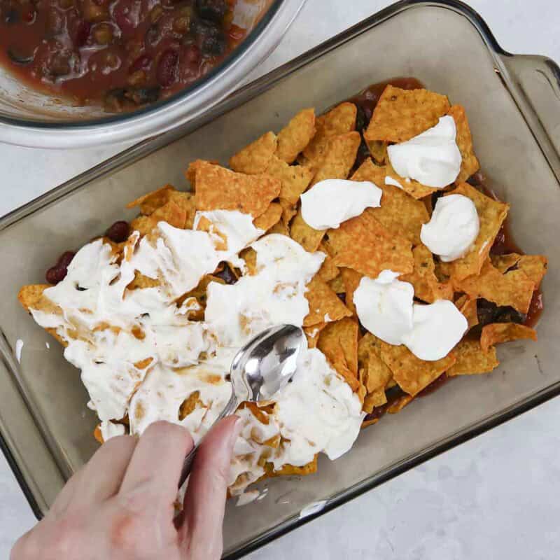 Overhead view of process shot 3 - add a layer of doritos and spread the sour cream over the Doritos.