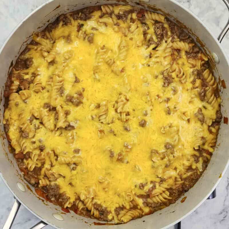 Overhead view of process shot 4 - turn off the heat and sprinkle the cheese over the top and replace the lid for 1 minute until the cheese melts.