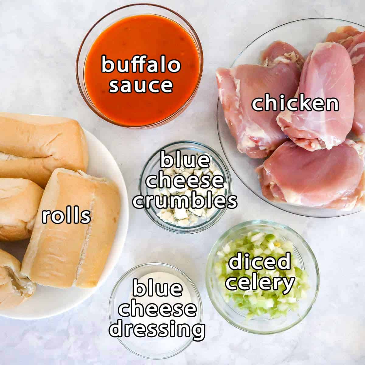 Overhead shot of ingredients - buffalo sauce, chicken, blue cheese crumbles, rolls, blue cheese dressing, and diced celery.