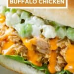 Side close up view of buffalo chicken sandwiches garnished with fresh herbs on a white plate.