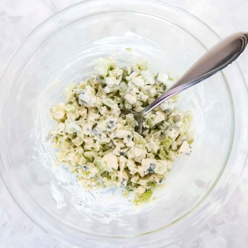 Overhead view of process shot 2 - mix together the celery, blue cheese crumbles, and blue cheese dressing. Refrigerate until ready to serve.