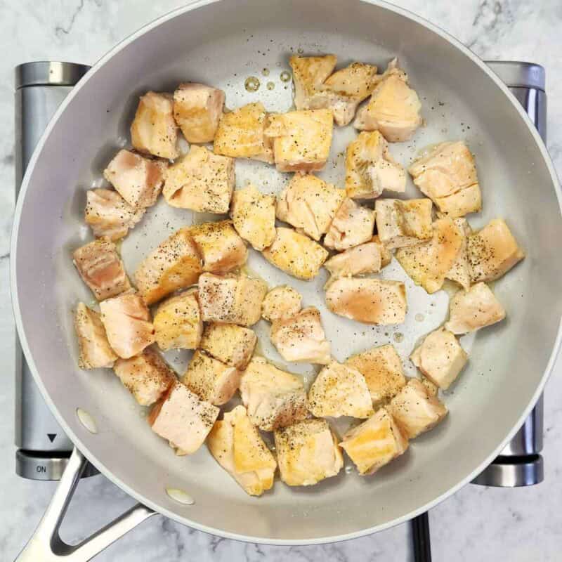 Overhead view of process shot 3 - add some oil to a non stick skillet and heat over medium -high heat. Add the salmon cubes in a single layer. Let them sear undisturbed for about 2 minutes until golden, then flip and cook for another 1-2 minutes.