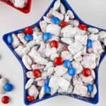 Overhead shot of patriotic muddy buddies in a blue star bowl with more M&Ms on the side.