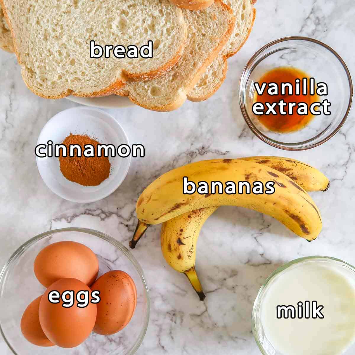 Overhead shot of ingredients - bread, vanilla extract, cinnamon, bananas, eggs, and milk.