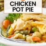 Side shot of chicken pot pie in a white bowl garnished with fresh parsley on a green cloth.
