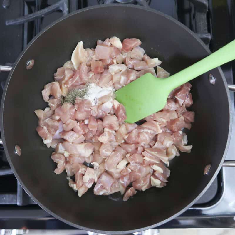 Overhead view of process shot 1 - heat the olive oil over medium-high heat in a large skillet. Then add the chicken, garlic salt, and pepper, and cook until the chicken is done.