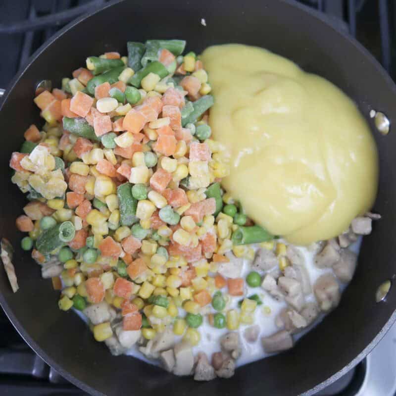 Overhead view of process shot 2 - mix in the vegetables, chicken soup, and milk, and cook until heated through.