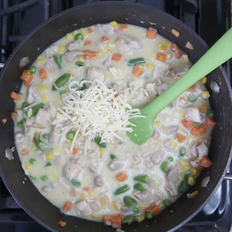 Overhead view of process shot 3 - stir ½ cup shredded cheddar cheese into the chicken/vegetable mix.