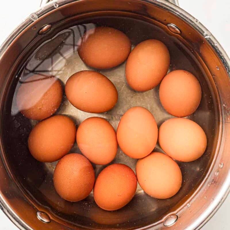 Overhead view of process shot 1 - hard boil the eggs. Drain and transfer the eggs to cold water until fully cooled.