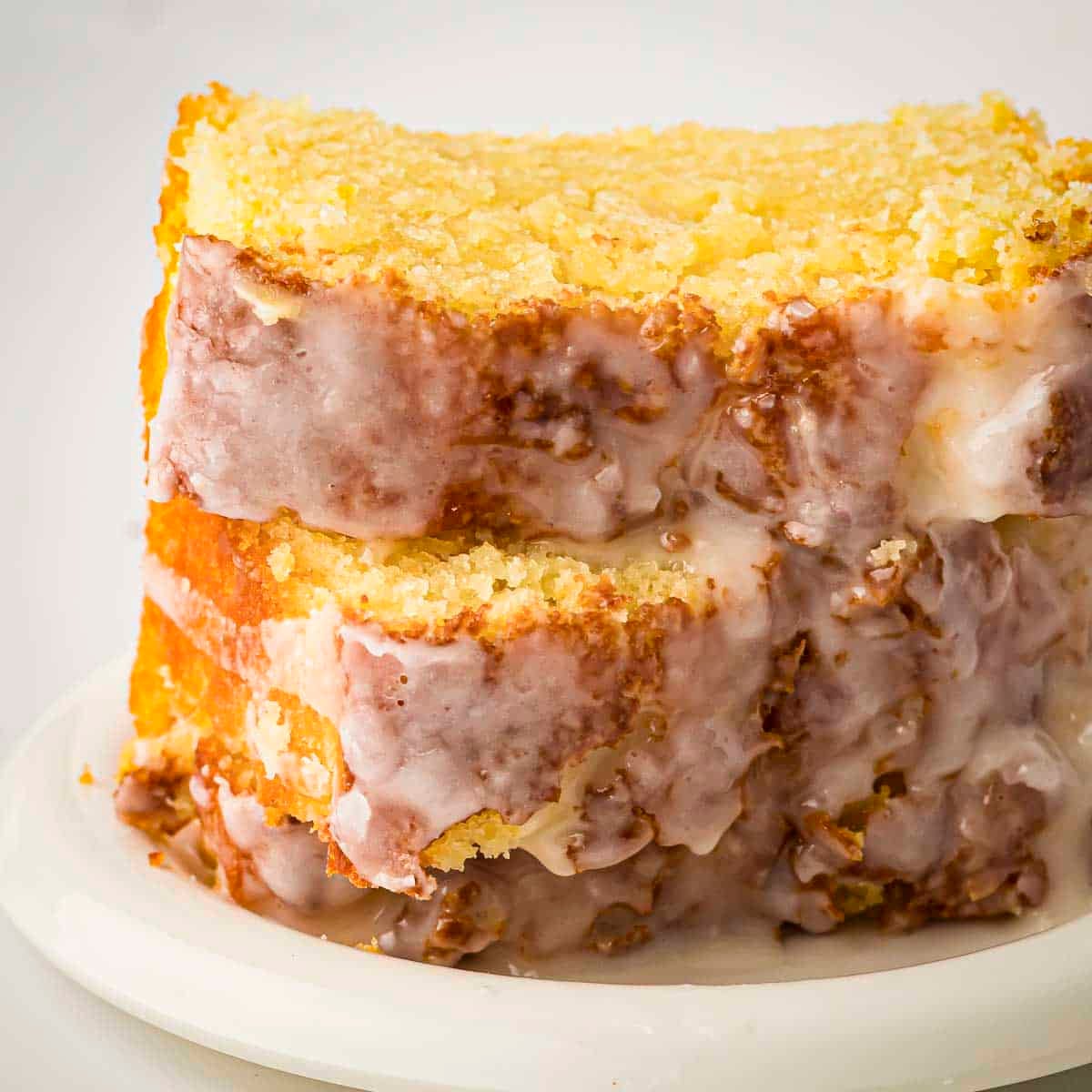 Side shot of two slices of lemon loaf cake stacked on a white plate.