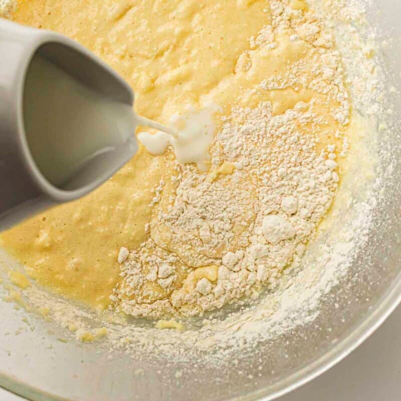 Overhead view of process shot 3 - in a separate bowl, whisk together the flour, baking powder, and salt. Then, add the dry ingredients to the batter alternately with the milk, mixing until just combined.