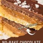 Side shot of two caramel bars sprinkled with flaky salt on a white surface.
