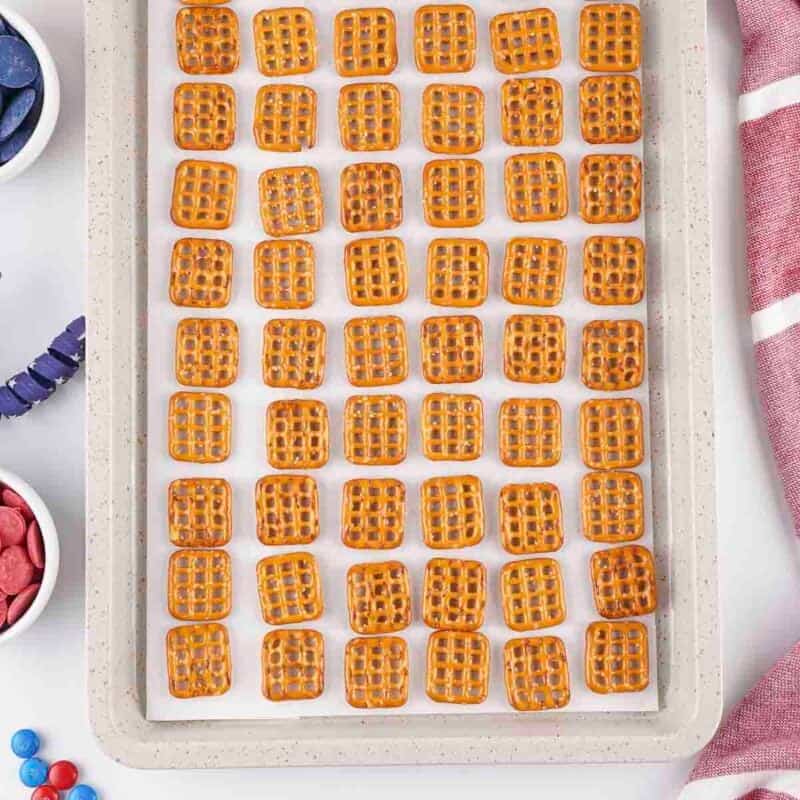 Overhead view of process shot 1 - line a 9x13 baking sheet with parchment paper and line the pretzels up on the pan, in one layer, leaving just a bit of room in between them.