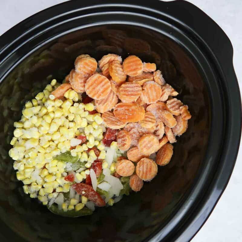 Overhead view of process shot 1 - combine frozen vegetables in the crock pot.