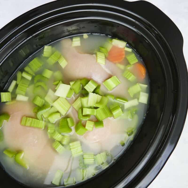 Overhead view of process shot 3 - add the diced celery and chicken broth. If desired, add the optional wine. Set crock pot to low and cook all day.