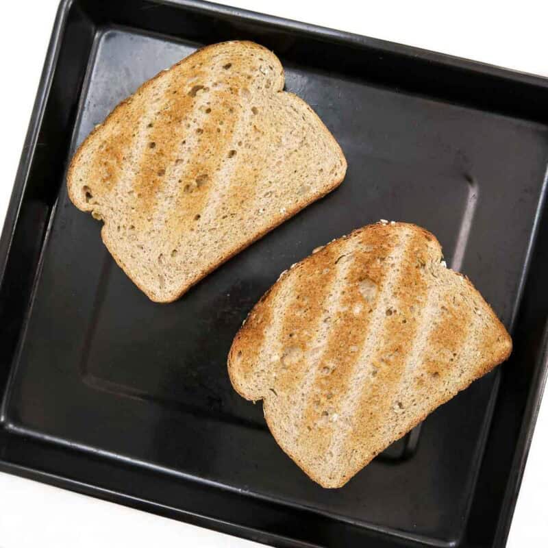 Overhead view of process shot 2 - lightly toast each slice of bread. Place the toasted bred on a baking sheet.