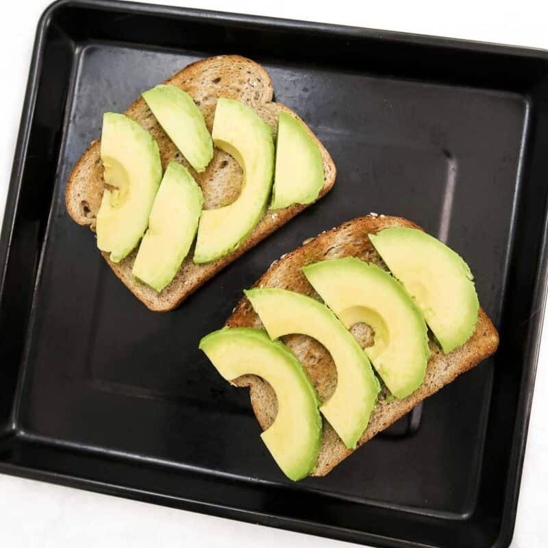 Overhead view of process shot 3 - distribute the avocado slices among the 4 pieces of bread.