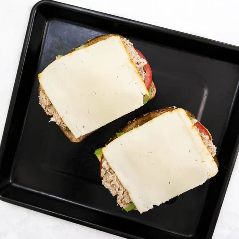 Overhead view of process shot 6 - place a slice of cheese on top of the tuna. Place the baking sheet under the broiler on high for 3-4 minutes until the sandwich is hot and cheese is melted.
