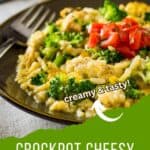 Side shot of cheesy chicken and rice garnished with herbs and fresh tomatoes in a brown bowl with a fork on the side.
