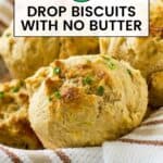 Side shot of golden brown biscuits garnished with chives in a bowl wrapped in a white striped cloth.