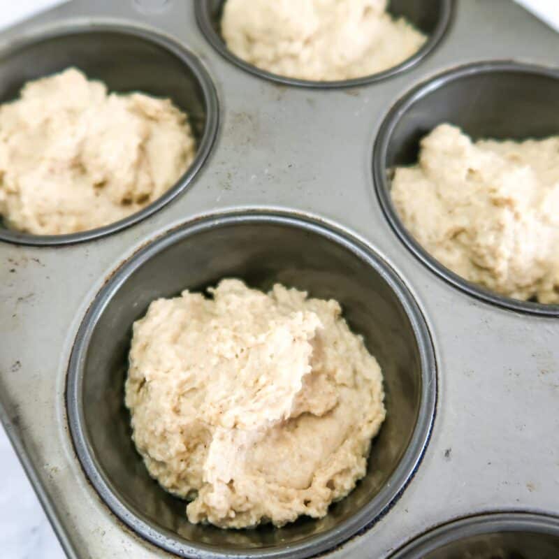 Close up view of process shot 4 - spray your muffin tin with nonstick spray. Drop dough into each muffin hole so that they are filled about ¾ of the way.