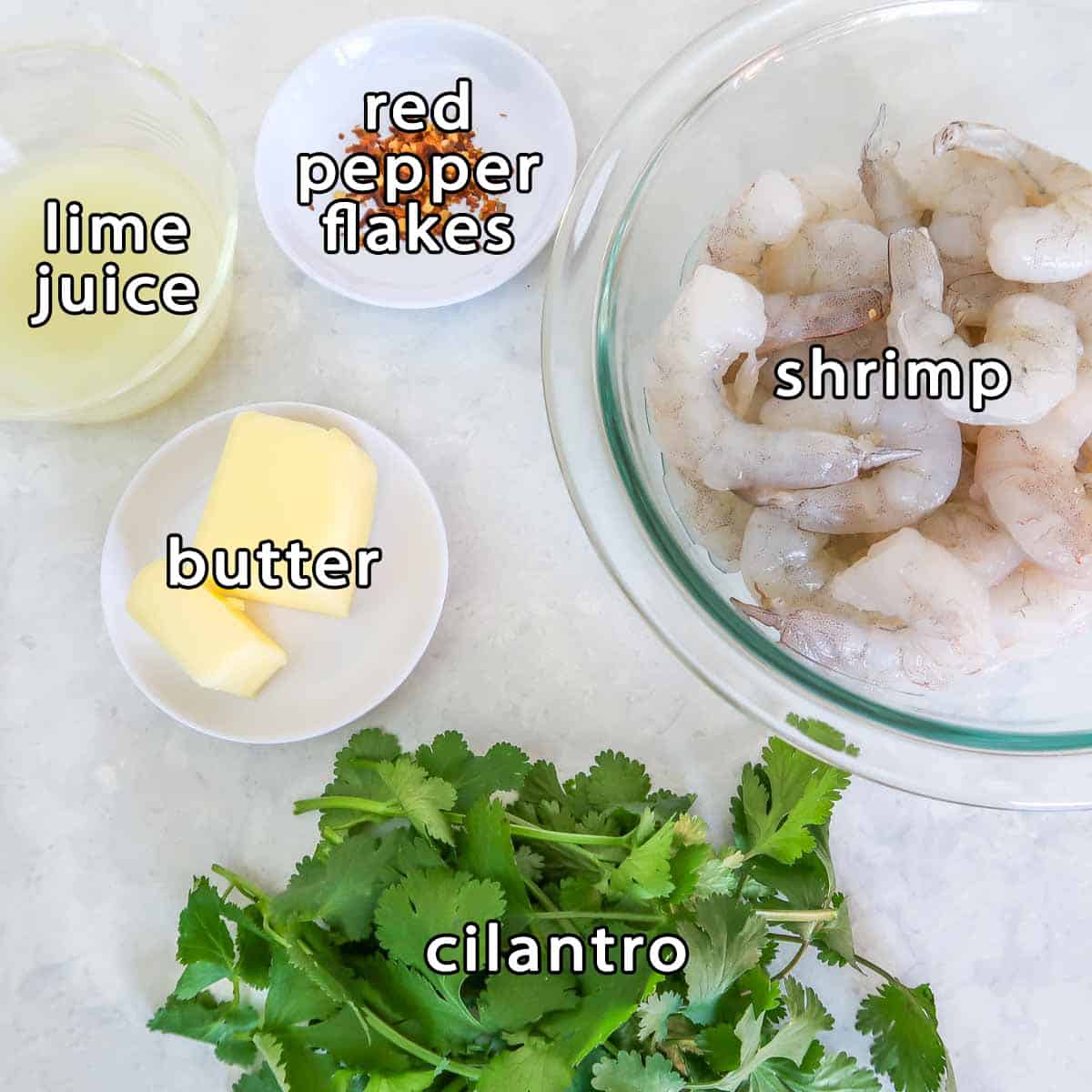 Overhead shot of ingredients - shrimp, lime juice, butter, red pepper flakes, and cilantro.
