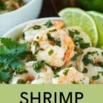 Close up shot of butter lime shrimp garnished with fresh parsley and lime wedges in a white bowl on a wooden surface.