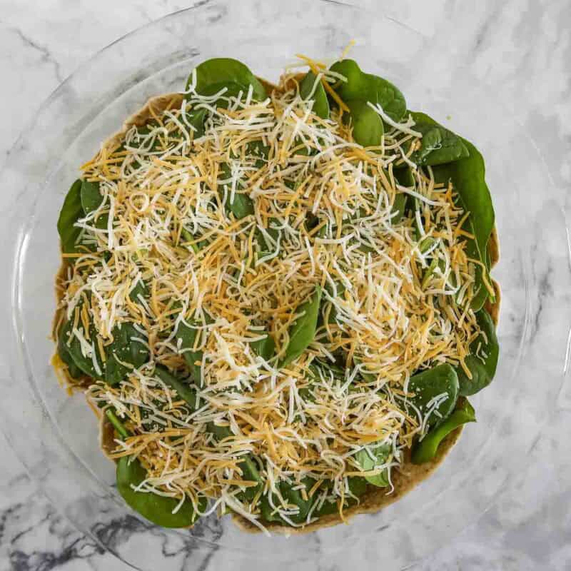 Overhead view of process shot 3 - spread out the handful of spinach and top with about a third of cheese.